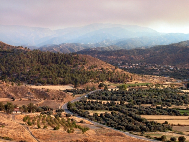 Figure 14: The Karkotis Valley with Mount Olympus behind, looking south, with the church of Panayia Kousouliotissa (BU0094; left), Dodekaskala (TS11; in olive groves in centre), and the village of Korakou (right). Photograph: Michael Given.