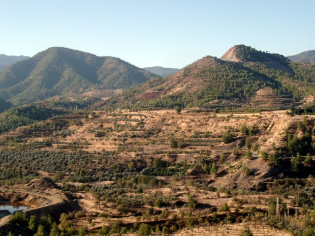 Figure 53: View from Memi mine south-west towards Alestos mine (the mountain in background), with Mavrovouni slag heap (TP006) visible as a black heap in the centre foreground. Photograph: Michael Given. 