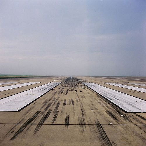 Concrete runway with black skid marks and grey blue sky