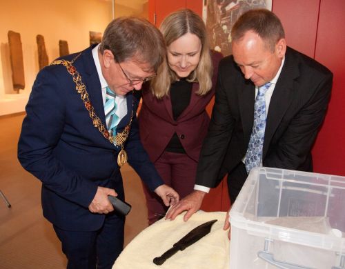 Maurice Hurley reveals a wooden Viking Age weavers' sword to the Lord Mayor of Cork, Councillor Fitzgerald and Ambassador Else Berit Eikeland