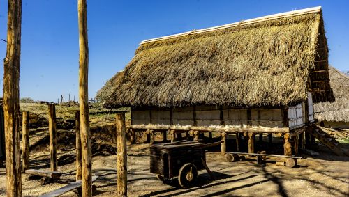 Reconstructed wooden house on posts with thatched roof