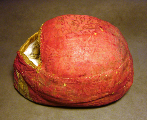 The Turku skull relic viewed from the side showing ornate red fabric with gold thread 
