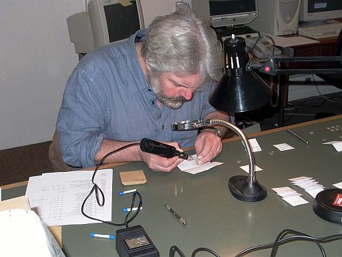 Matthew Ponting looking through a magnifying glass drilling into a Roman coin
