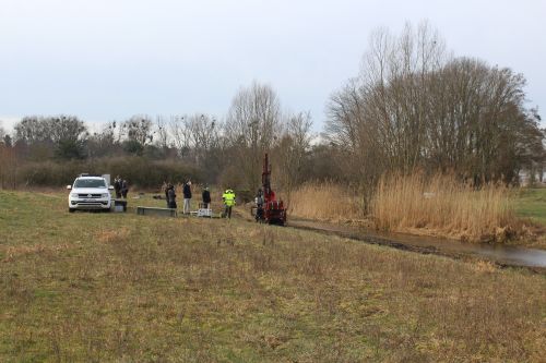People and machinery alongside a small watercourse and vegetation