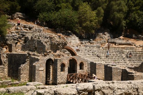 Archaeological ruins of steps and walls with tourists exploring them