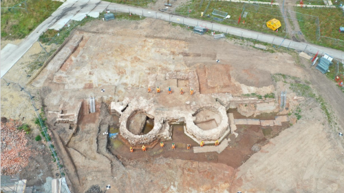 Aerial photo with small figures dressed in hi-vis standing either side of the excavated gatehouse