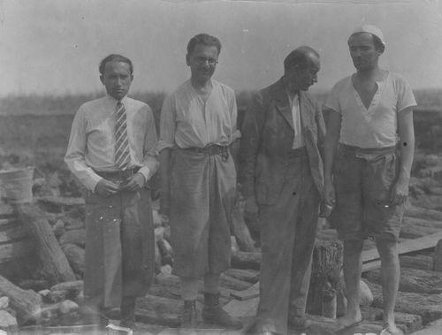 Black and white photograph of 4 people standing while on an excavation site 