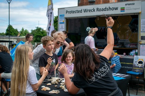 Members of the public handling archaeological objects during an outreach event